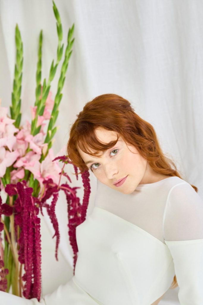 Braut sitzt vor einer Vase mit außergewöhnlichen Blumen