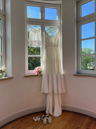Brautkleid und Taufenkleid aufgehangen in einem Turmzimmer in Kiel.