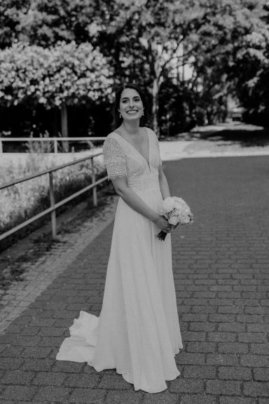 Braut mit Brautkleid von vorne mit einem Brautstrauß in den Händen.