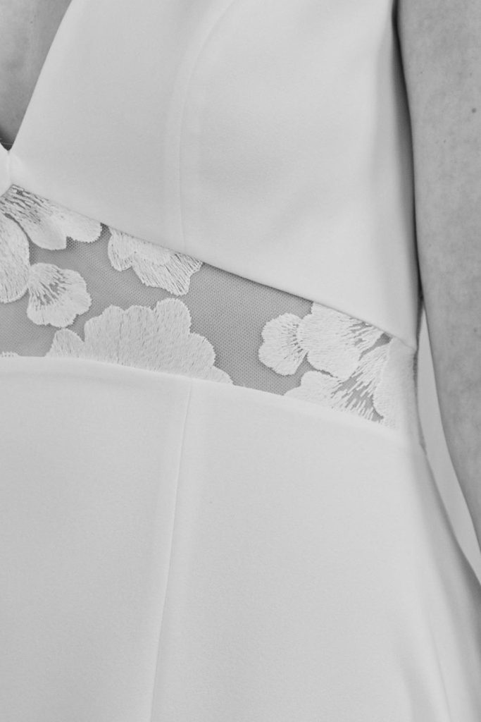 Detailausschnitt der Blumenspitze auf einem Brautkleid aus Crepe-Stoff.
