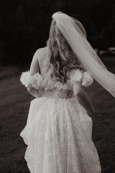 Braut von hinten in einem romantischen Blütenkleid mit Schleier