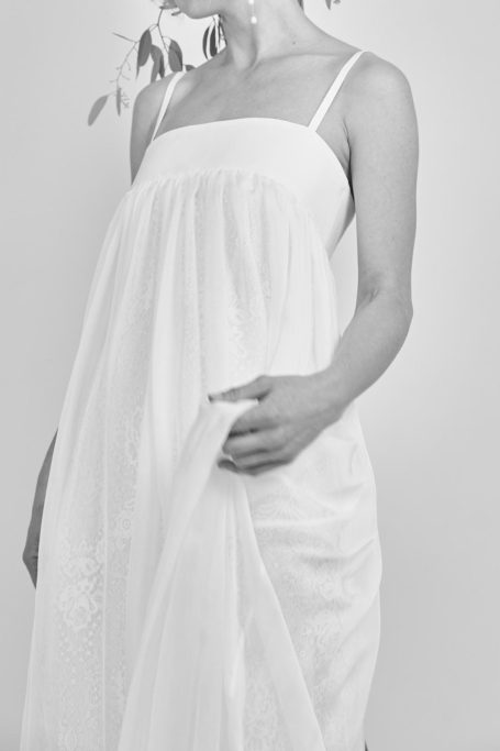 Braut streift durch leichten Stoff vom Brautkleid. Der Spitzenstoff darunter ist leicht zu sehen.
