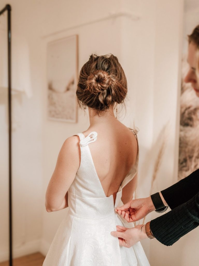 Braut bekommt ein A-Linie-Brautkleid angezogen