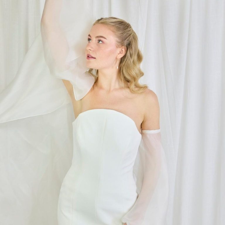 Braut trägt cleanes Brautkleid in A-Linie und einem besonderem Federn und Strass.