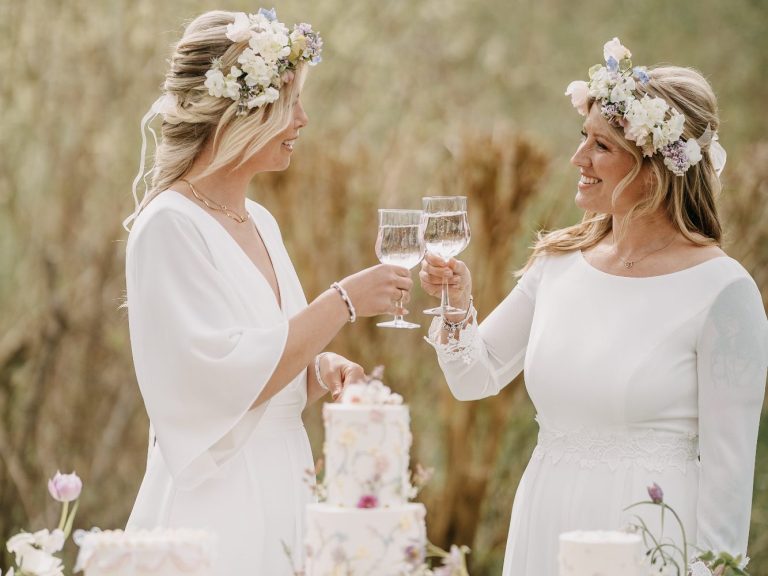 Ein lesbisches Paar auf ihrer Hochzeit in Kiel beim anstoßen. Tolle Jumper statt Brautkleider und schwedische Blumenkränze.